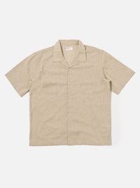 The Beige Fine Organic Cotton Sal Road Shirt is shown as a flat lay against a white background. The short-sleeve shirt features a single-piece camp collar with a loop closure at the top, a straight hem, and two symmetrical patch pockets on the chest. The organic cotton fabric has a soft marled beige texture.
