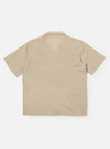 The Beige Fine Organic Cotton Sal Road Shirt is shown from the back as a flat lay against a plain white background. The image highlights the shirt's straight hem, short sleeves, and the soft marled texture of the beige organic cotton fabric.