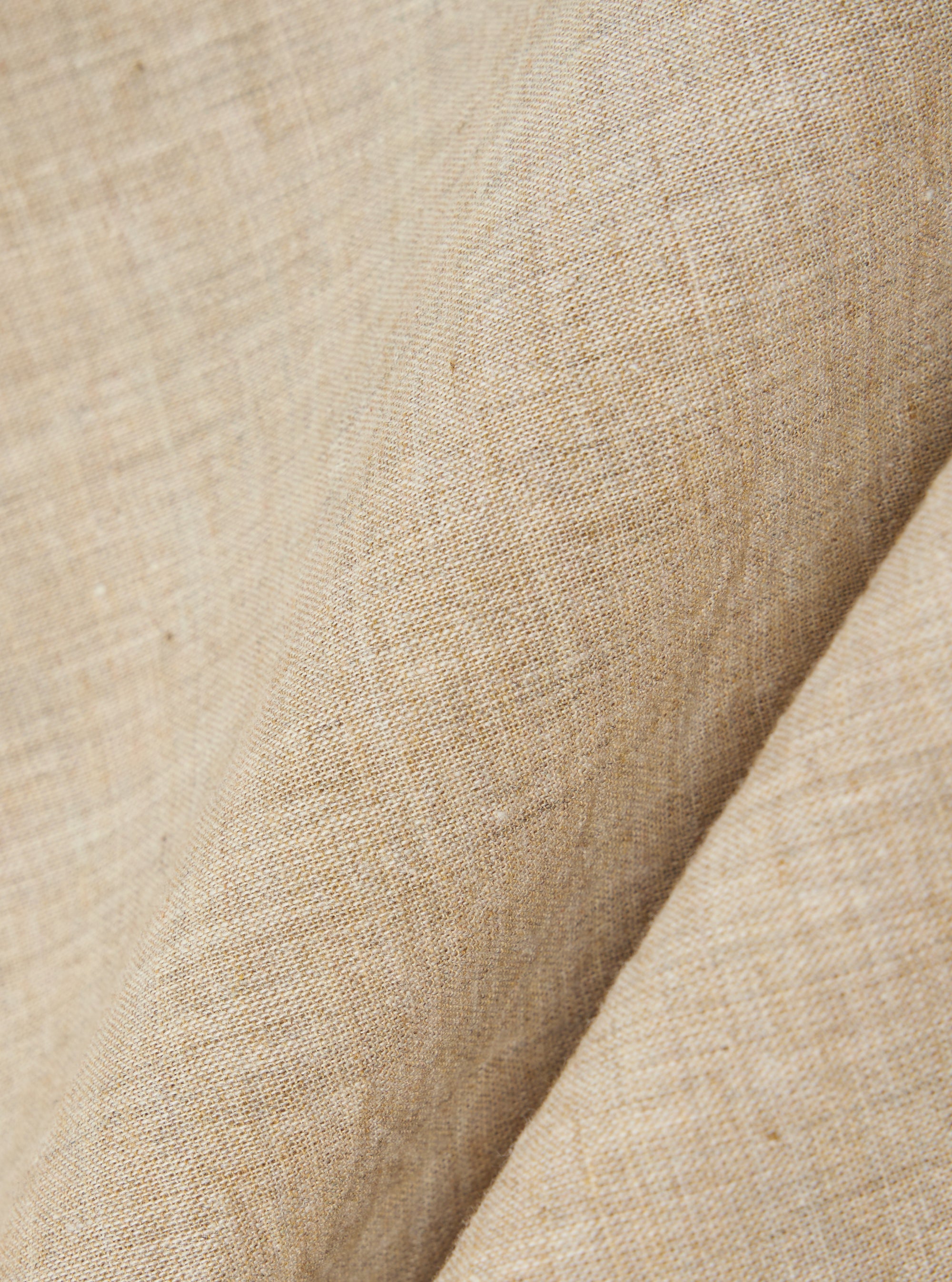 A close-up fabric swatch of the Beige Fine Organic Cotton Sal Road Shirt highlights the soft marled texture and lightweight loose weave of the organic cotton material. The image focuses on the blended beige threads and the detailed construction of the fabric.