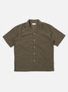 The Brown Fine Organic Cotton Sal Road Shirt is shown as a flat lay against a white background. The shirt features a relaxed camp collar, a button-down front, and short sleeves. A single patch pocket is visible on the chest. The fabric is a smooth, lightweight organic cotton in a solid brown color.