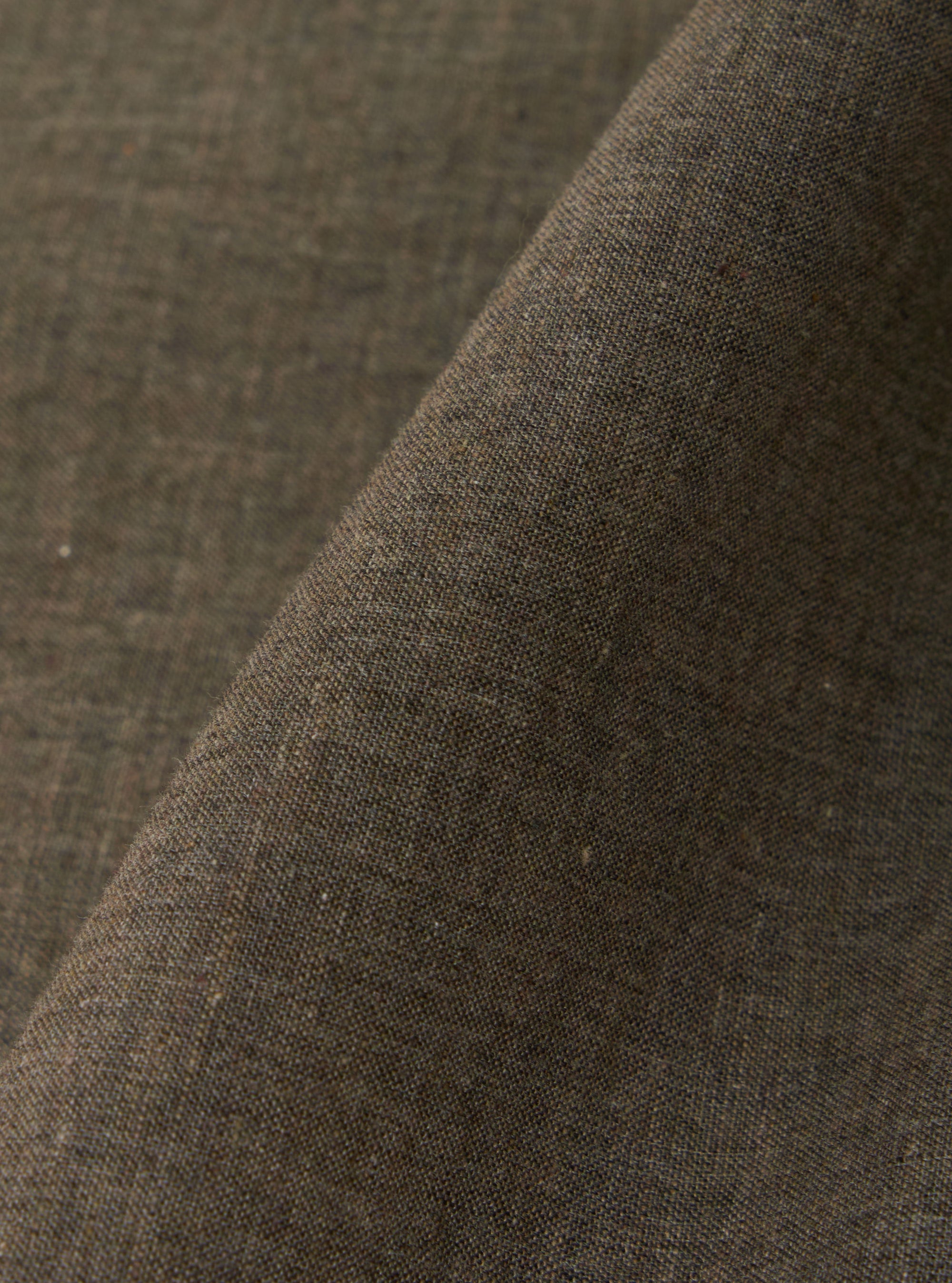 A close-up fabric swatch of the Brown Fine Organic Cotton Sal Road Shirt highlights the lightweight, loose weave of the 100% organic cotton. The image focuses on the rich brown color and the fine texture of the material.