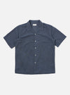 The Indigo Fine Organic Cotton Sal Road Shirt is shown as a flat lay against a plain white background. The shirt features a camp collar, a central button-down front with tonal buttons, and two large chest patch pockets with buttoned flaps. The fabric is a deep indigo blue organic cotton with a smooth, lightweight appearance.