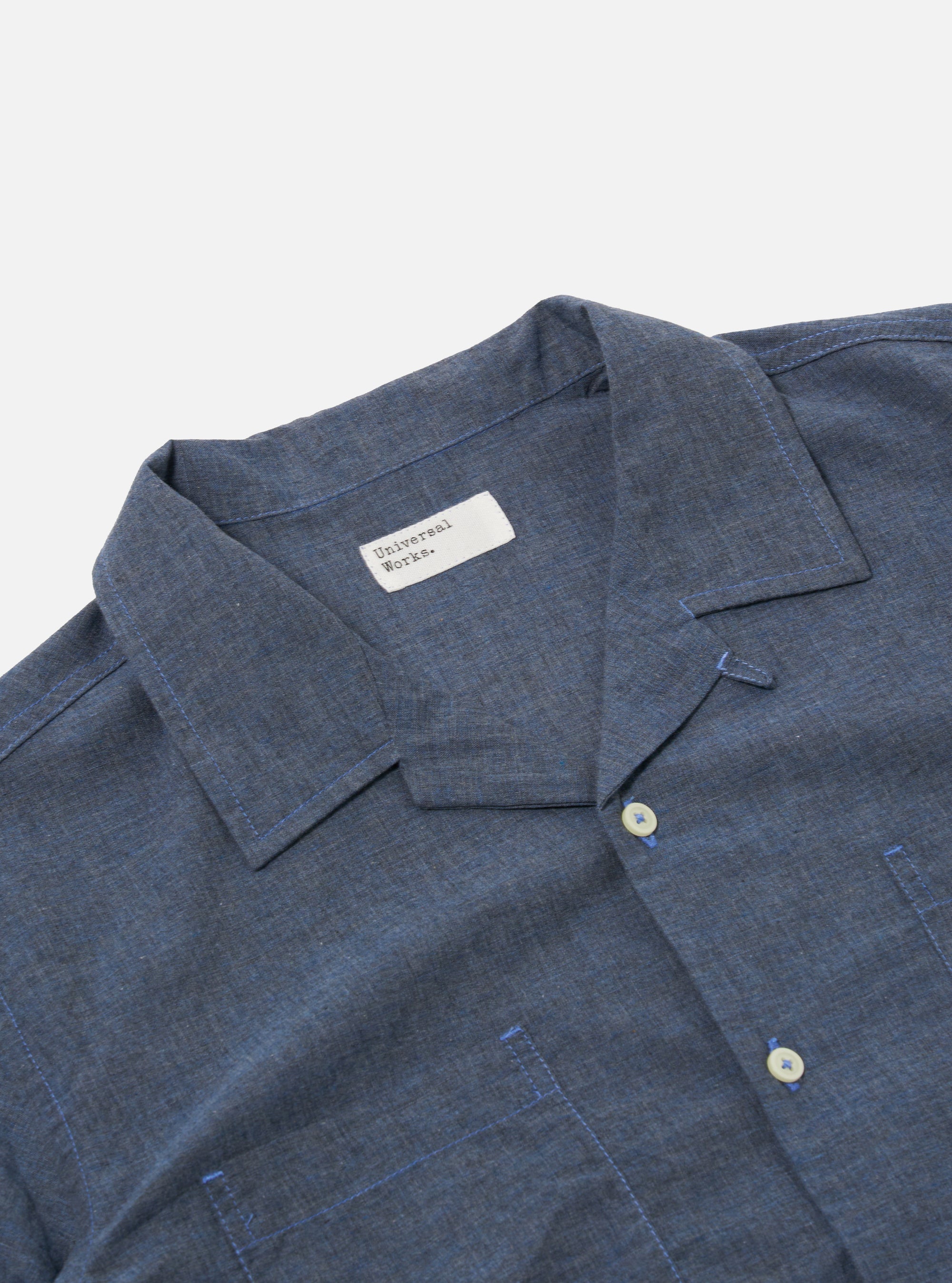 The Indigo Fine Organic Cotton Sal Road Shirt is shown from the back as a flat lay against a plain white background. The image highlights the shirt's straight hem and the soft marled texture of the indigo organic cotton fabric.