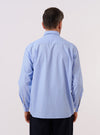 A model wears the Sky Fil A Fil Square Pocket Shirt against a neutral studio background. The shirt features a prominent square chest pocket on the left side and a classic button-down front with a pointed collar. The light blue end-on-end fabric weave is visible as the model poses to show the shirt's fit and length.