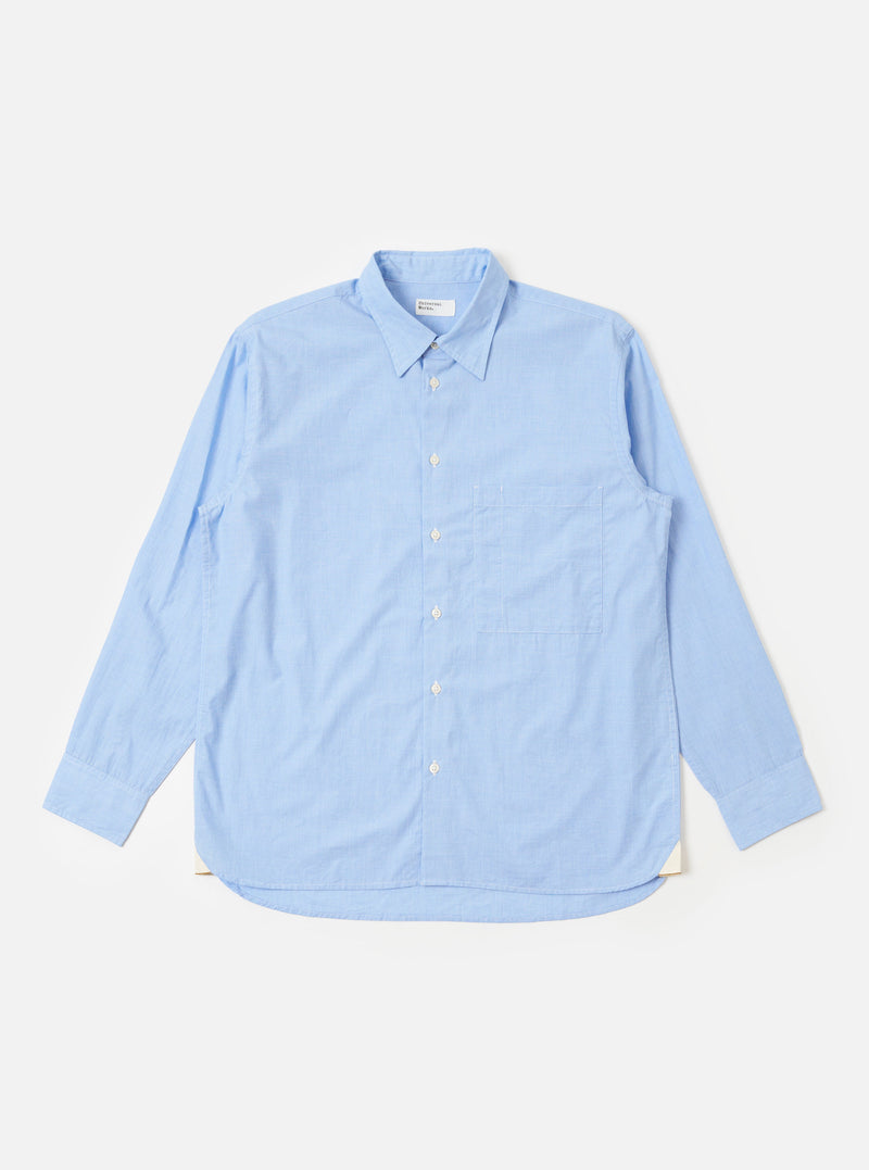 The Sky Fil A Fil Square Pocket Shirt is shown as a flat lay against a white background. The shirt features a button-down front, a classic collar, and a large oversized square chest pocket on the left side. The fabric has a fine sky blue and white fil-a-fil weave.