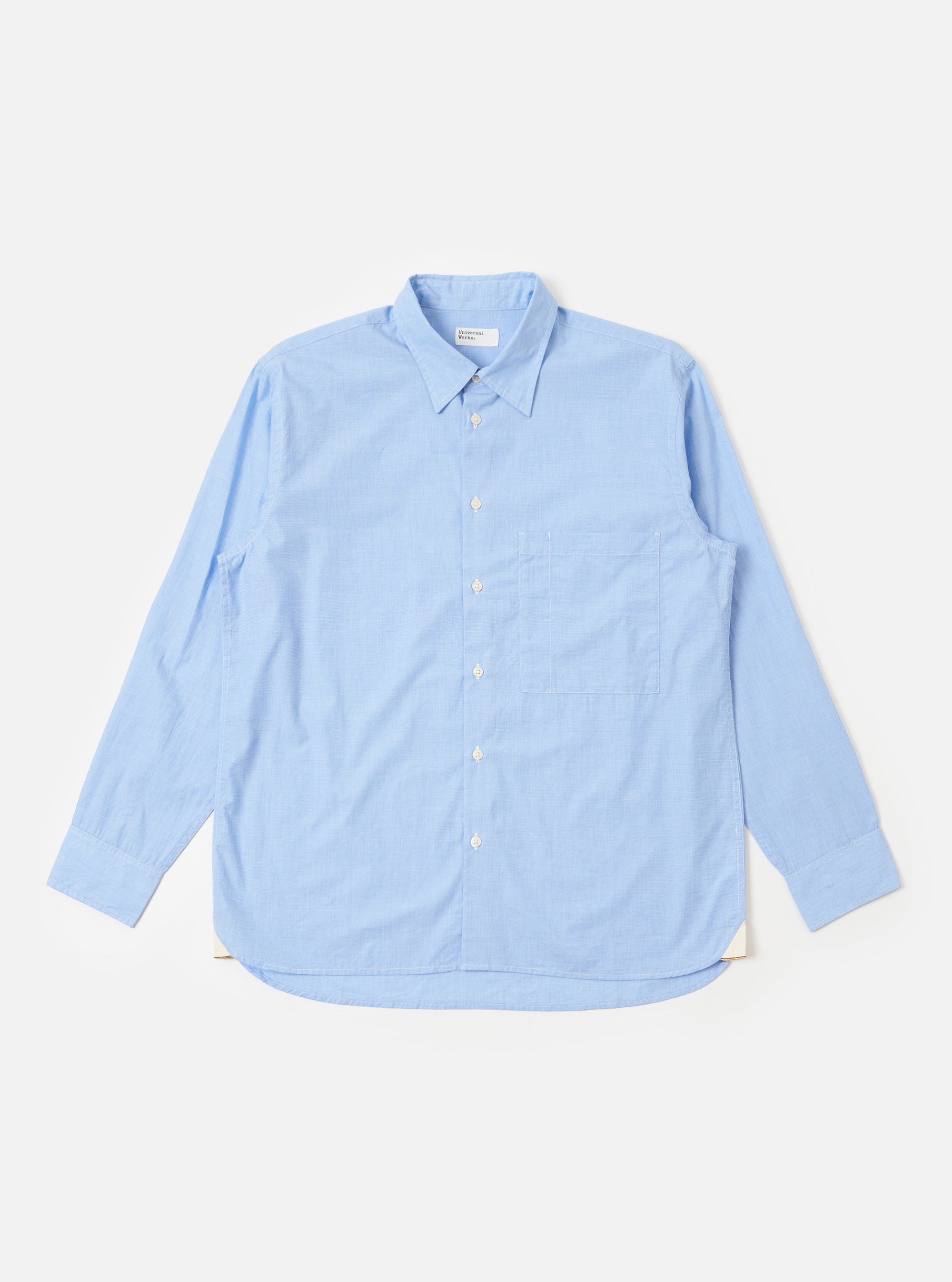 The Sky Fil A Fil Square Pocket Shirt is shown as a flat lay against a white background. The shirt features a button-down front, a classic collar, and a large oversized square chest pocket on the left side. The fabric has a fine sky blue and white fil-a-fil weave.