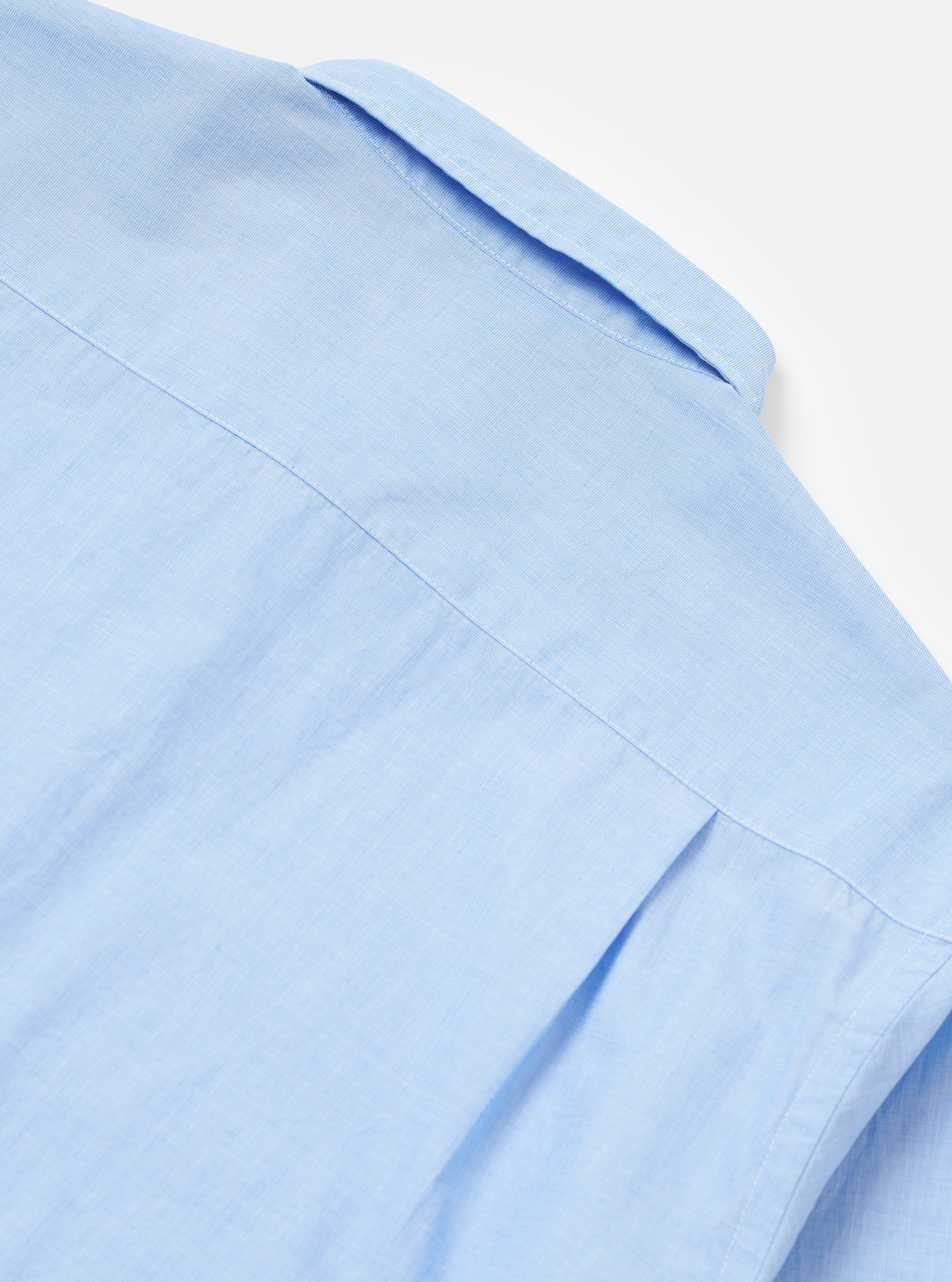 The Sky Fil A Fil Square Pocket Shirt is shown from the back as a flat lay against a white background. The shirt features a clean back yoke and long sleeves with buttoned cuffs. The light blue fil-a-fil cotton fabric has a fine, textured appearance.