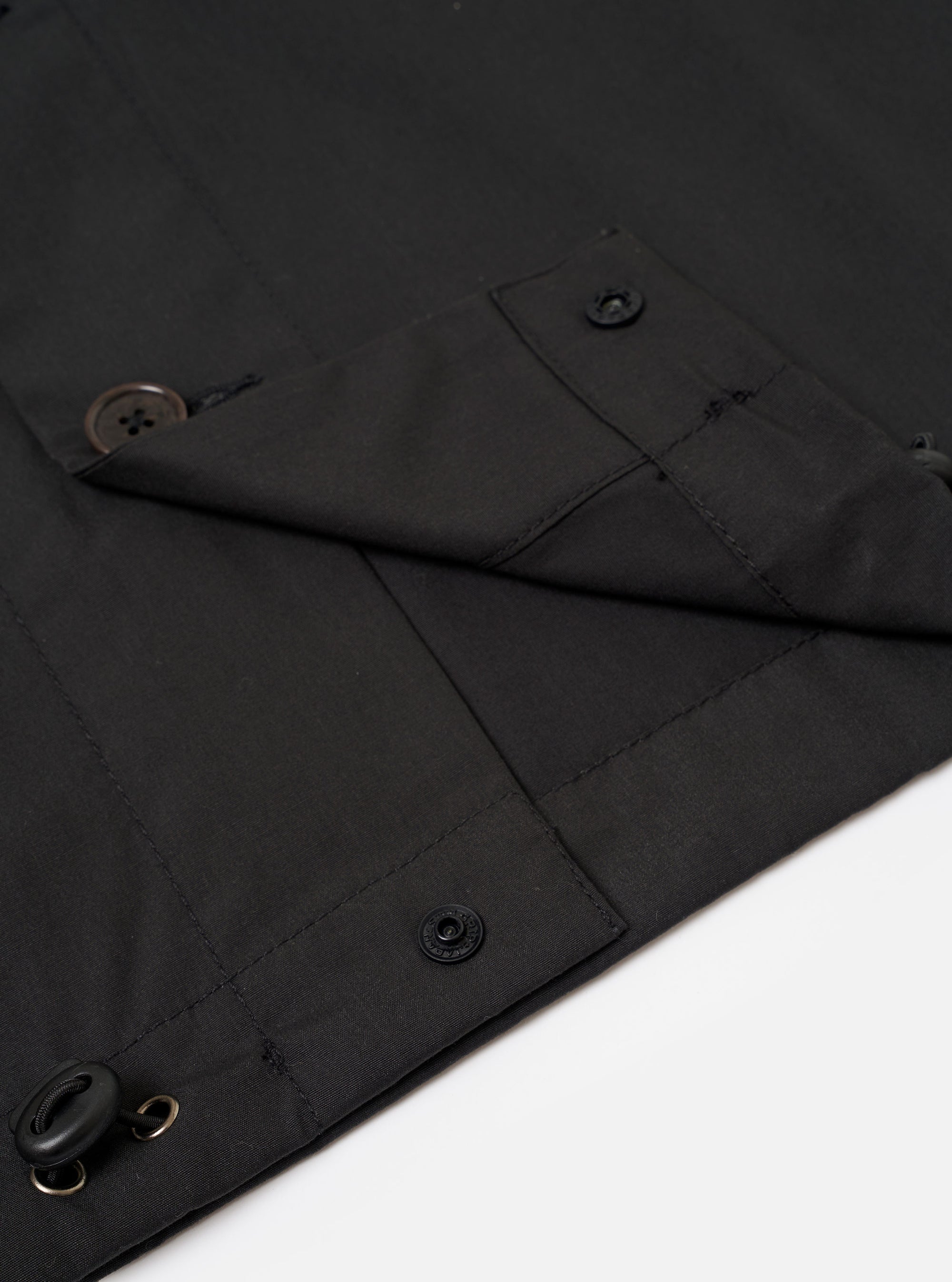 The Black Recycled Polytech Z Tech Overshirt is shown in a detail view as a flat lay against a plain white background. The image highlights the smooth, technical texture of the black recycled polytech fabric and the construction of the reinforced chest pocket with a horizontal zip closure.