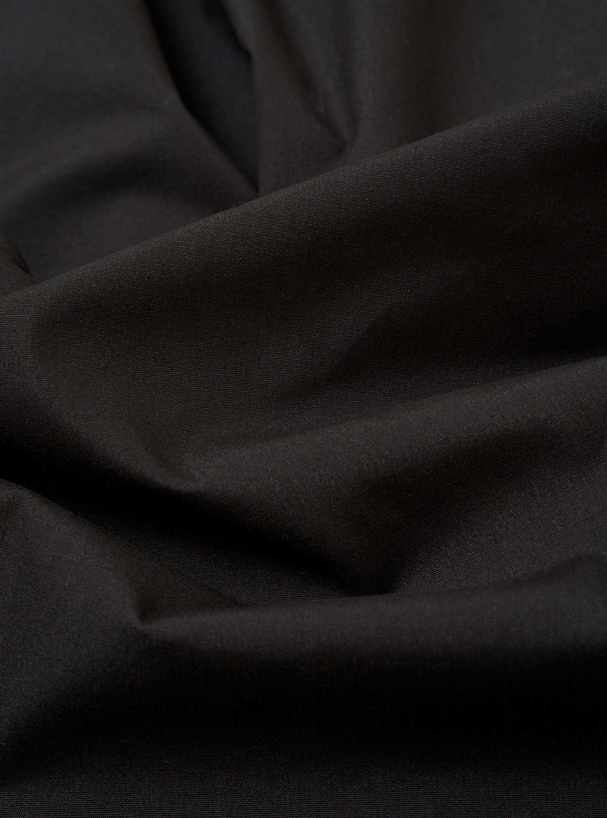 The Black Recycled Polytech Z Tech Overshirt is shown from the back as a flat lay against a plain white background. The image highlights the garment's back yoke with a central box pleat and the smooth texture of the black recycled polytech fabric.