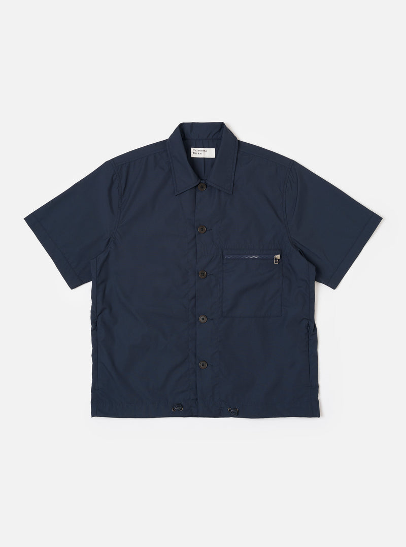 The Navy Recycled Polytech Z Tech Overshirt is shown as a flat lay against a white background. The short-sleeve overshirt features a boxy silhouette, a one-piece collar, and a full button-down front. A prominent reinforced patch pocket with a visible zipper is located on the left chest. The fabric is a smooth, dark navy recycled polytech.