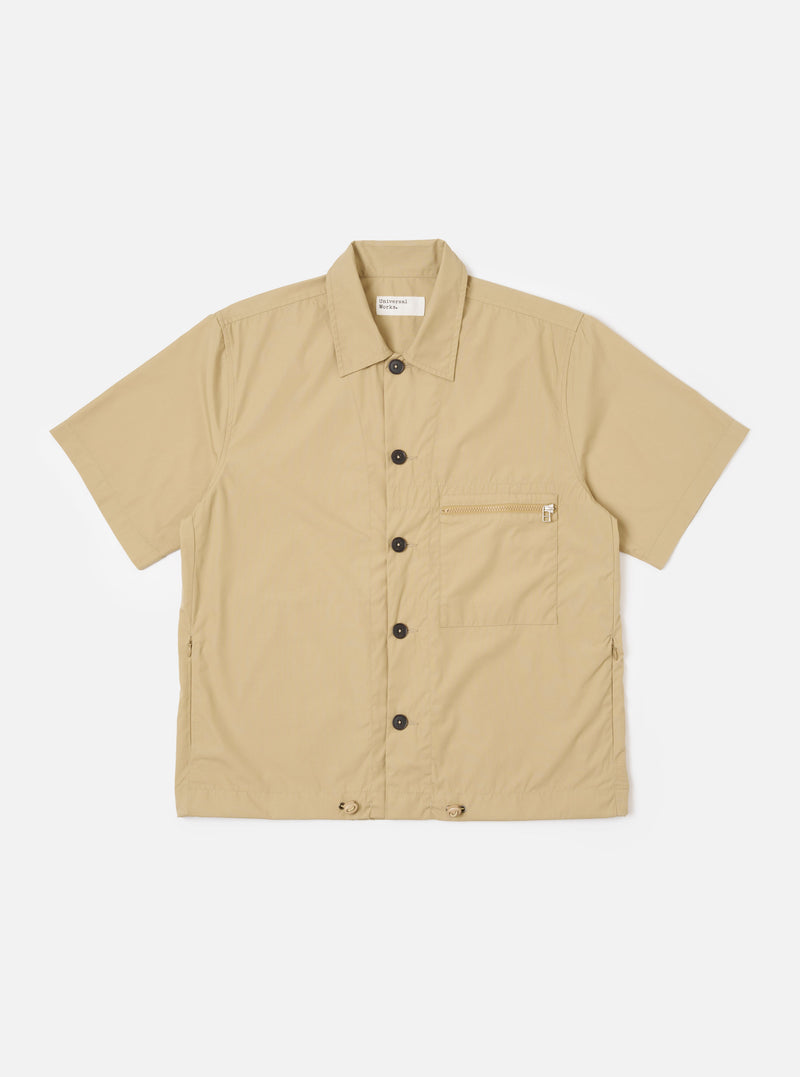 The Sand Recycled Polytech Z Tech Overshirt is shown as a flat lay against a white background. The overshirt features a one-piece collar, a central front closure, and a single reinforced vertical zip pocket on the left chest. The sand-colored fabric has a smooth, technical finish, and the garment is designed with a boxy fit and a straight hem.