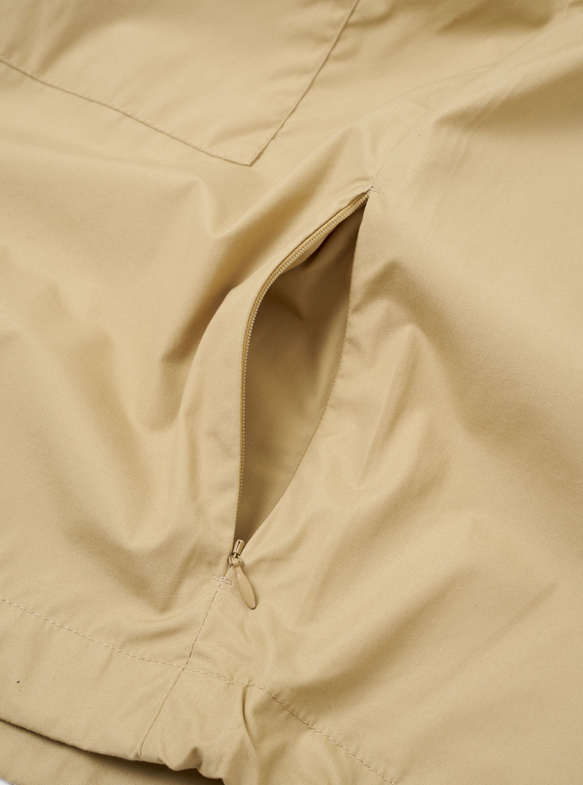 The Sand Recycled Polytech Z Tech Overshirt is shown in a detail view as a flat lay against a plain white background. The image highlights the smooth texture of the sand-colored recycled polytech fabric and the construction of the vertical zip chest pocket.