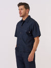 A model wears the Navy Recycled Polytech Z Tech Overshirt against a plain white background. The overshirt features a one-piece collar, a central button-down closure, and a prominent reinforced patch pocket on the left chest with a vertical zip. The dark navy fabric has a smooth, technical finish, and the garment is designed with a boxy, straight fit.