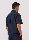 A model wears the Navy Recycled Polytech Z Tech Overshirt, shown from a rear three-quarter angle against a plain white background. The overshirt features a structured collar, long sleeves, and a clean, utility-style back construction with a straight hem. The dark navy fabric has a smooth, technical finish.