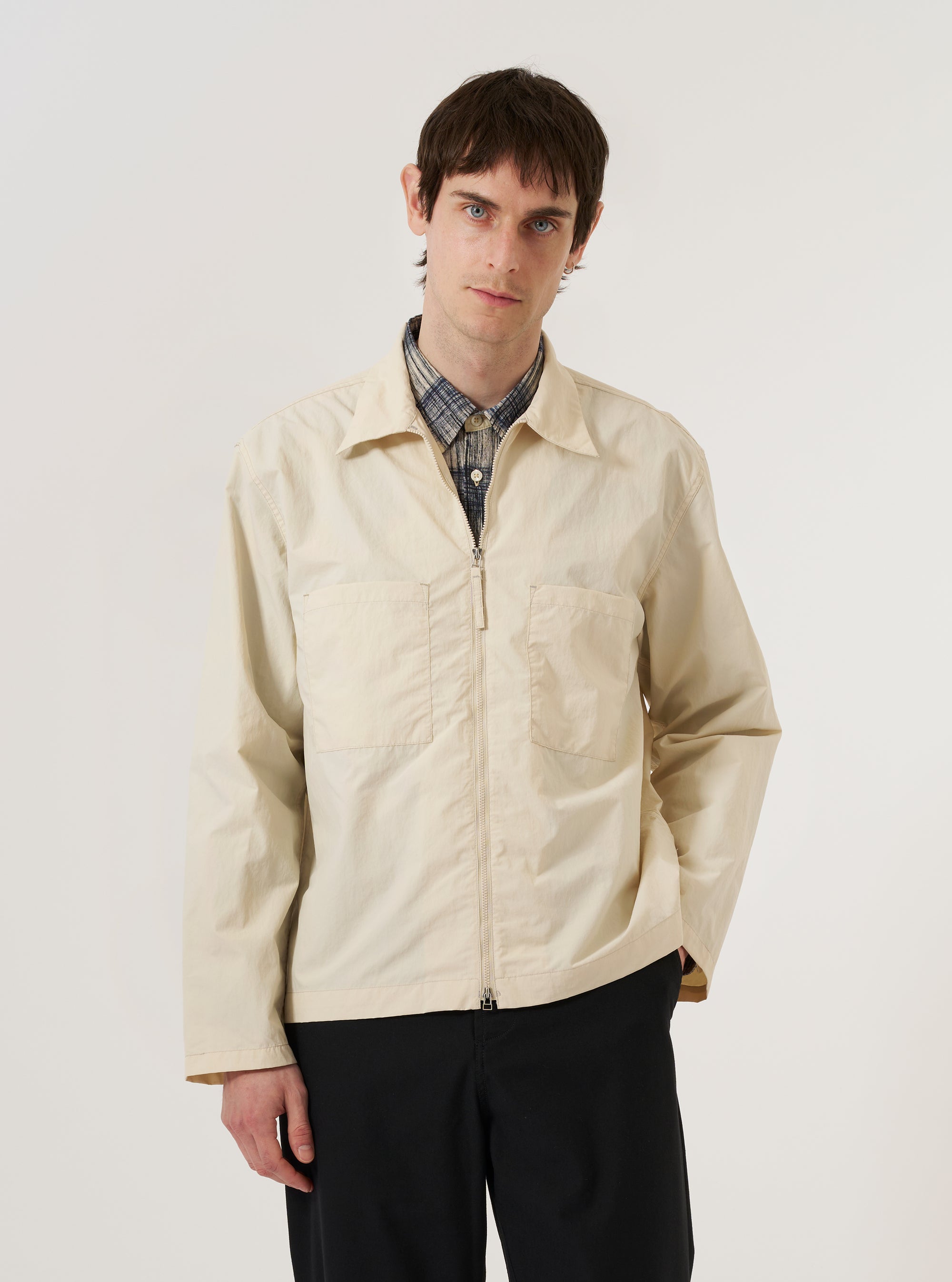 A model wears the Stone Seo Recycled Nylon Zip Too Shirt against a plain white background. The shirt features a two-way zip-front closure, a classic point collar, and two large patch pockets on the chest. The garment is constructed from a stone-colored recycled nylon fabric with a smooth, technical finish. The model is shown in a front-facing view, highlighting the shirt's relaxed fit and straight hem.