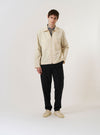 The Stone Seo Recycled Nylon Zip Too Shirt is shown as a flat lay against a plain white background. The shirt features a full-length central zip closure, a classic pointed collar, and two large patch pockets on the chest. The garment is made from a smooth, stone-colored recycled nylon fabric.