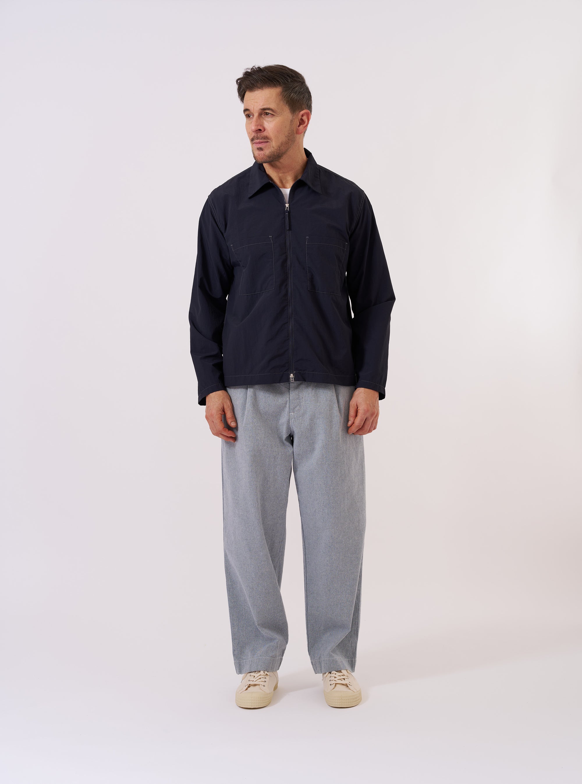 The Navy Seo Recycled Nylon Zip Too Shirt is shown as a flat lay against a plain white background. The shirt features a full-length central zip closure, a classic collar, and two large patch pockets on the chest. The fabric is a smooth navy blue recycled nylon with a slight technical sheen.
