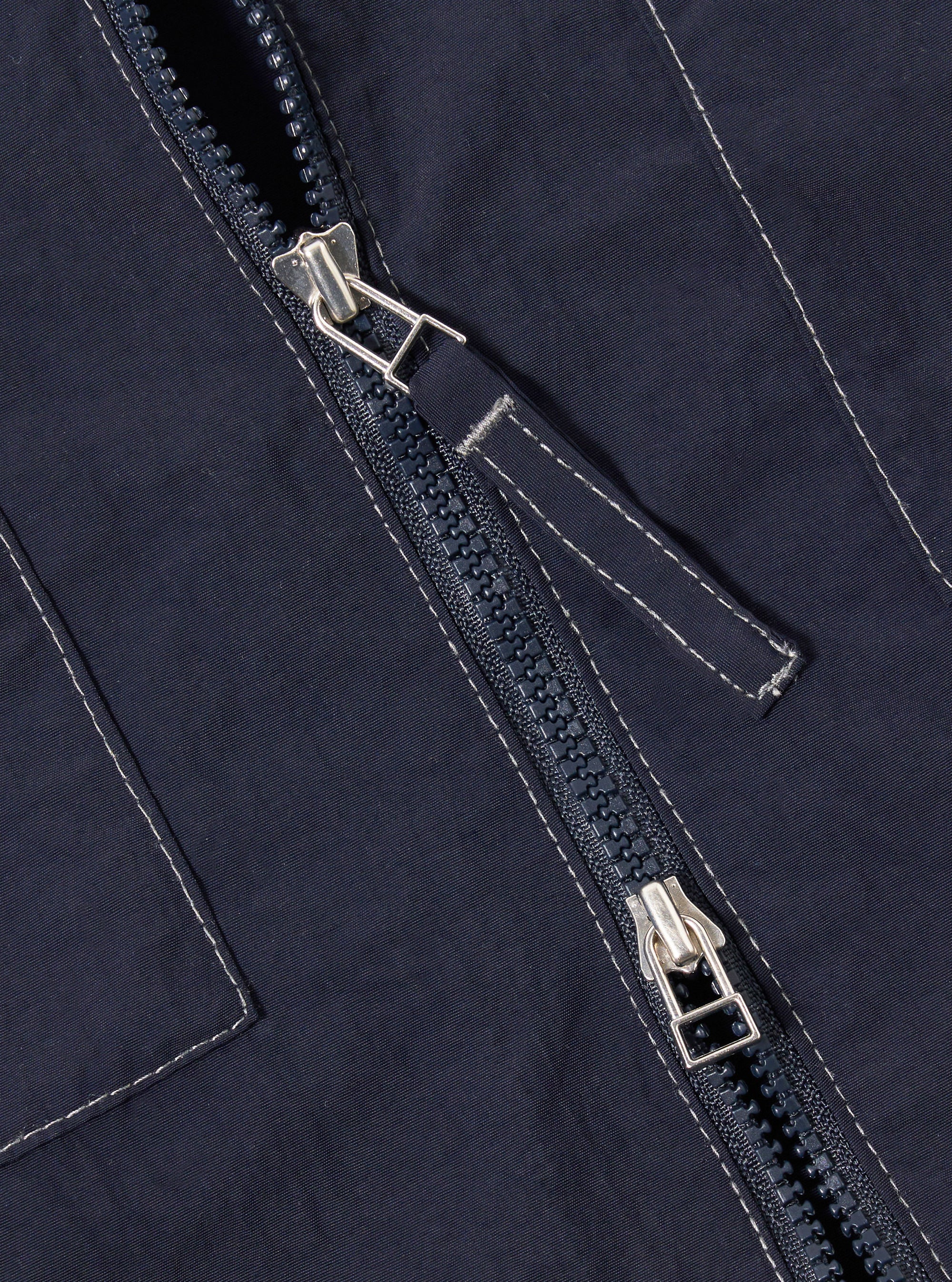 The Navy Seo Recycled Nylon Zip Too Shirt is shown in a detail view as a flat lay against a plain white background. The image highlights the technical texture of the dark navy recycled nylon fabric, focusing on the construction of the chest pockets and the silver-tone metal zipper.
