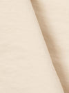 A close-up fabric swatch of the Stone Seo Recycled Nylon Zip Too Shirt highlights the light stone color and the smooth, technical texture of the recycled nylon material. The fabric fills the frame, providing a detailed view of the garment's weave and color.