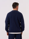 A model wears the Navy Brush Back Sweat Billy Sweat, shown from the back against a plain white background. The sweatshirt features a relaxed fit, a classic crew neck, and ribbed detailing at the cuffs and hem. The garment is made from a solid navy blue cotton fabric with a soft, brushed-back finish. No mannequin is present in the image.