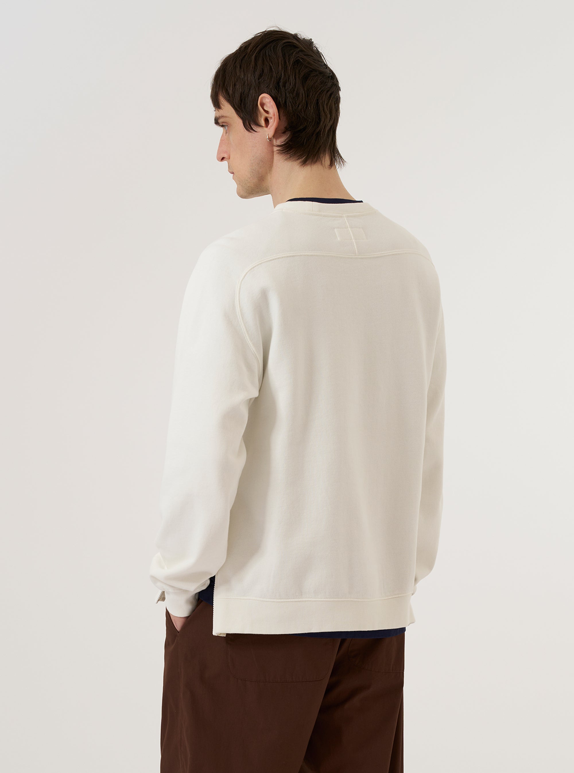 A model is wearing the Ecru Brush Back Sweat Billy Sweat, shown from the back against a plain white background. The sweatshirt features a relaxed fit with dropped shoulders, a ribbed crew neck, and ribbed detailing at the cuffs and hem. The garment is made from a solid ecru-colored fabric with a smooth finish. No mannequin is present in the image.