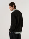 A model wears the Black Brush Back Sweat Billy Sweat, shown from the back against a plain white background. The sweatshirt features a relaxed fit, a classic crew neckline, and ribbed cuffs and hem. The black cotton fabric has a soft, matte finish.