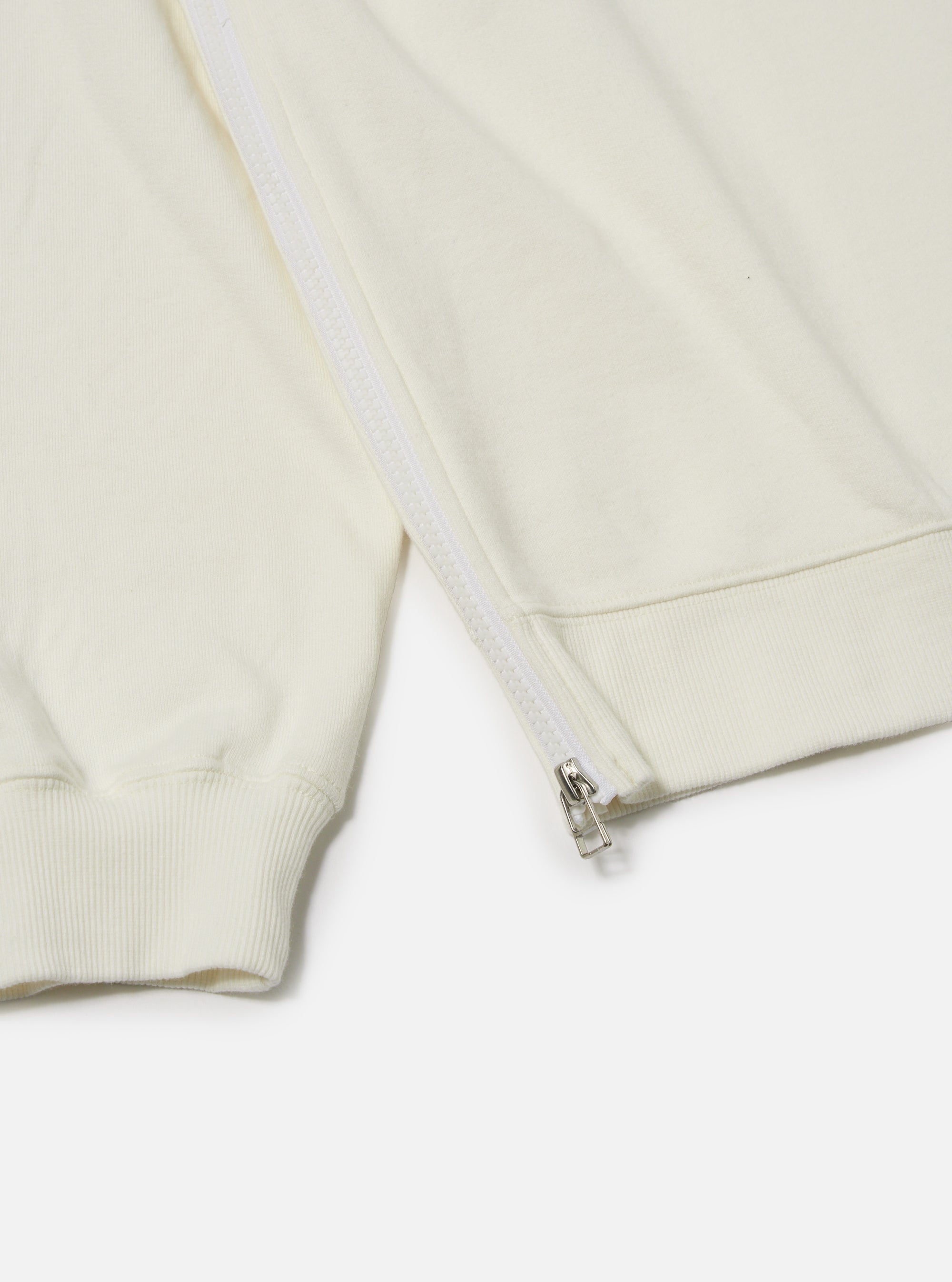 The Ecru Brush Back Sweat Billy Sweat is shown from the back as a flat lay against a plain white background. The image highlights the off-white color and soft texture of the garment, featuring a ribbed crew neck and a ribbed hem.