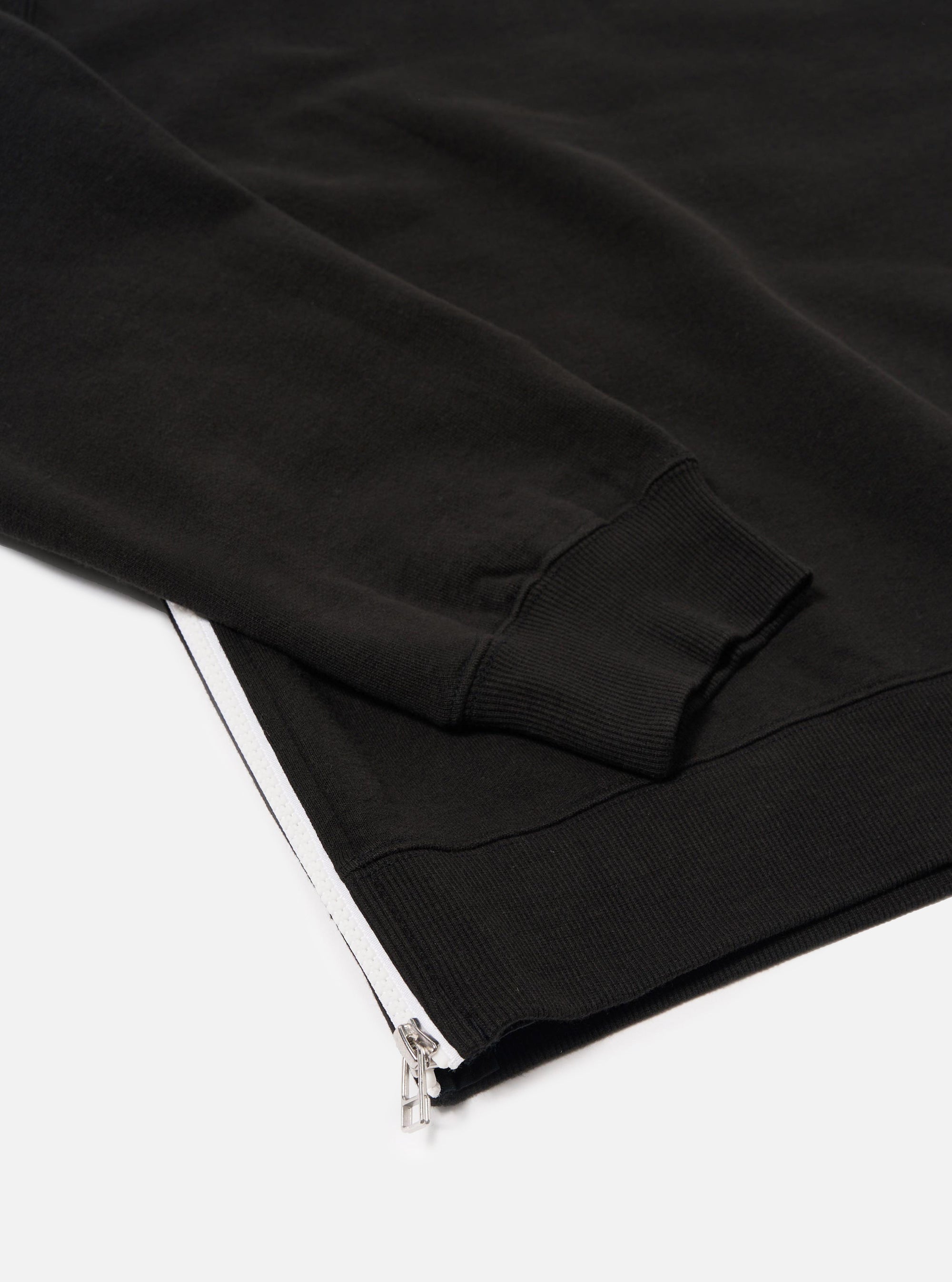 The Black Brush Back Sweat Billy Sweat is shown in a detail view as a flat lay against a plain white background. The image highlights the soft, brushed texture of the black cotton fabric and the ribbed detailing at the collar.