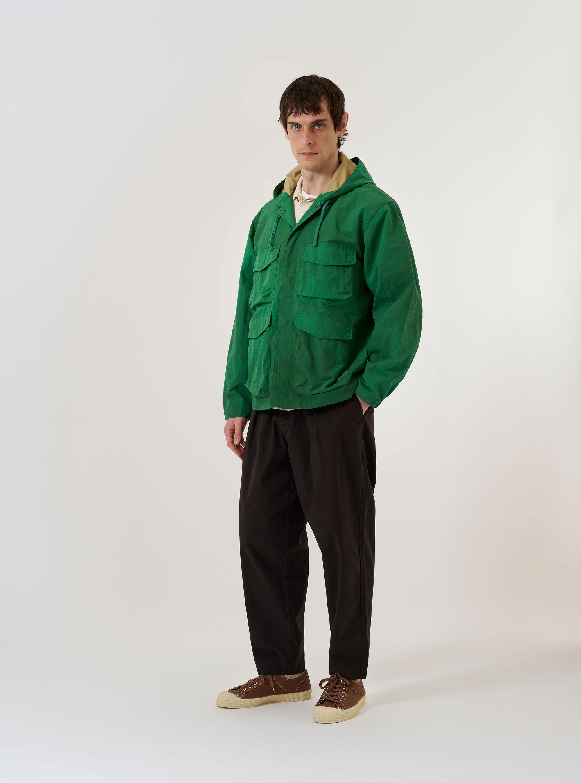 The Green Recycled Splash Nylon Longsands Jacket is displayed as a flat lay against a plain white background. The jacket features a hood with adjustable drawstrings, a central zip-front closure, and two large patch pockets at the waist. The fabric is a smooth, green recycled nylon with a subtle technical finish.