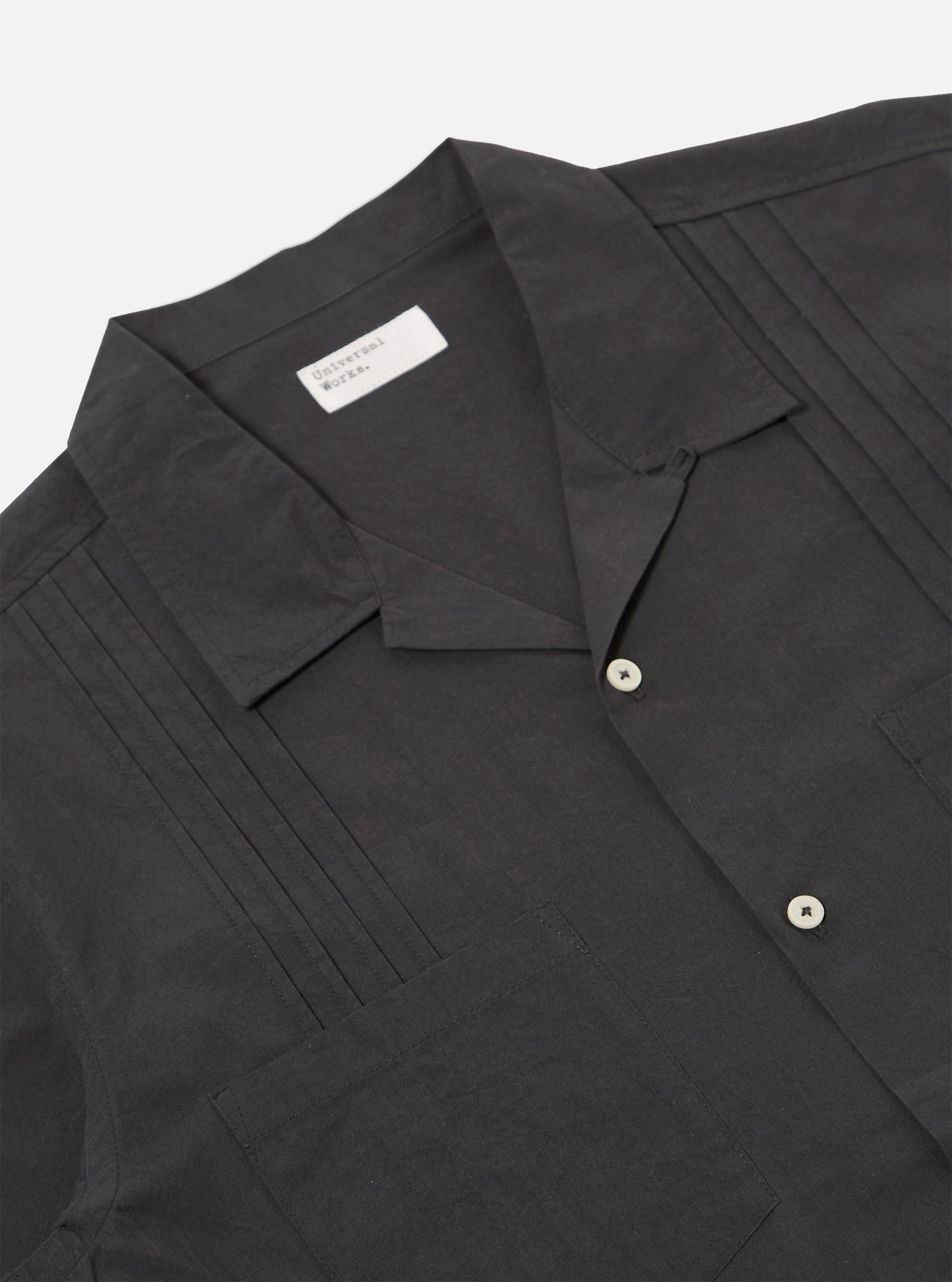 The Black Tech Cotton S/S Dwight Overshirt is shown from the back as a flat lay against a plain white background. The image highlights the short-sleeved, straight-hemmed construction of the garment and the smooth, crisp texture of the black tech cotton fabric.