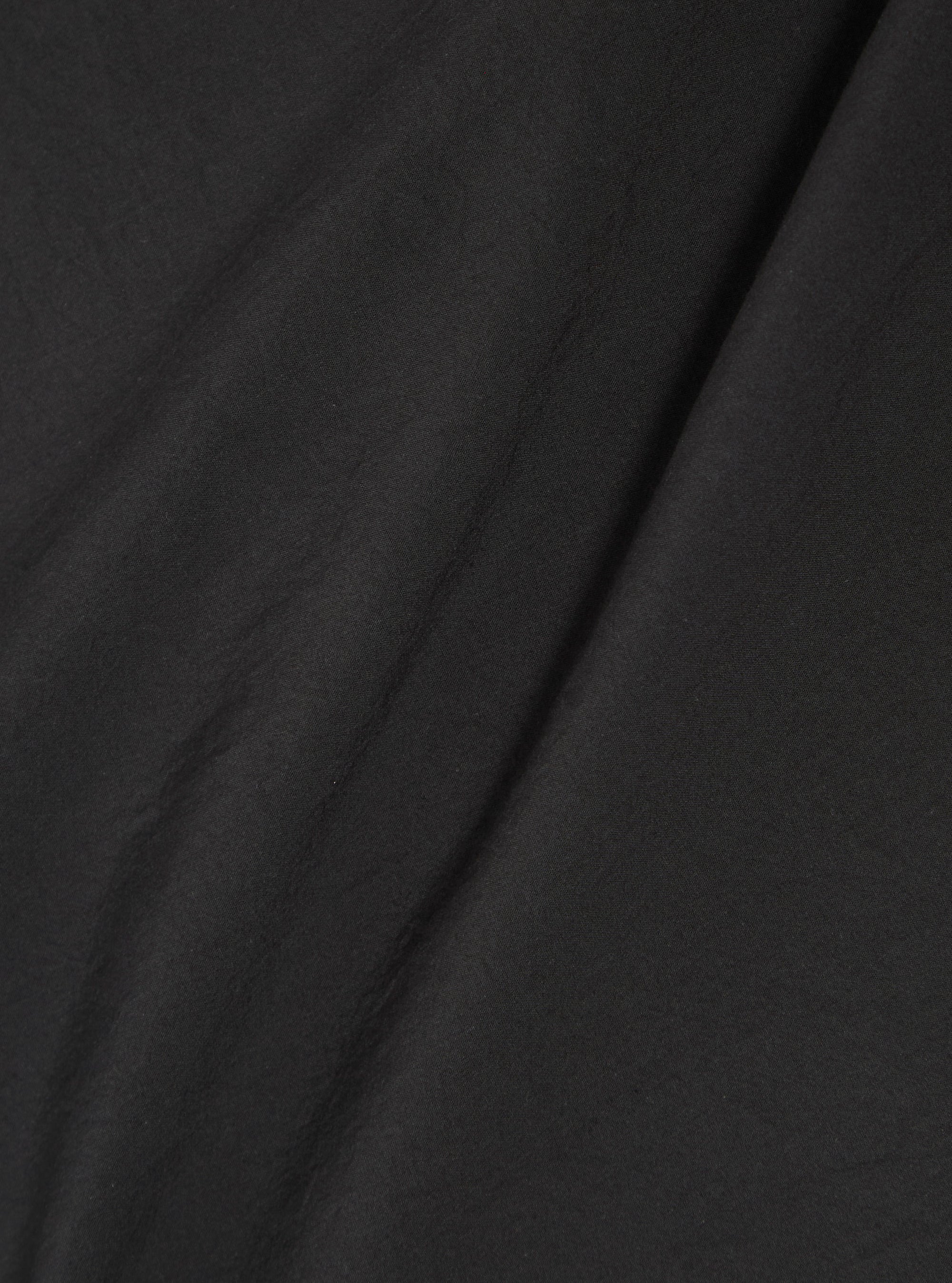 A close-up swatch image of the Black Tech Cotton S/S Dwight Overshirt fabric. The image focuses on the textile detail, showing a solid black color with a smooth, technical weave. The fabric fills the entire frame, providing a clear view of the material's texture and matte finish.