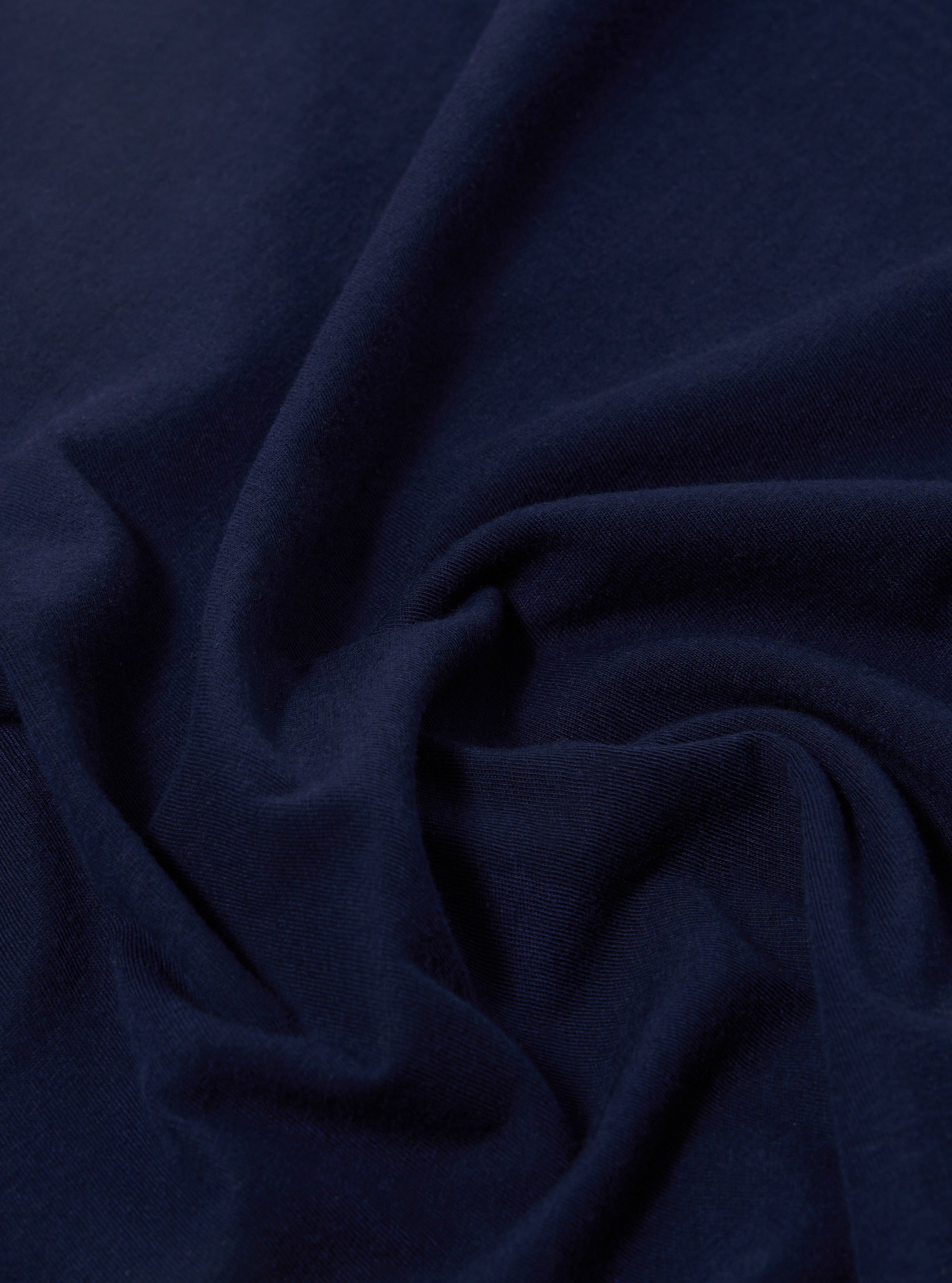A close-up swatch image of the Navy Single Jersey 34 Printed Core Tee highlights the deep navy blue color and the fine, smooth knit texture of the single jersey fabric.