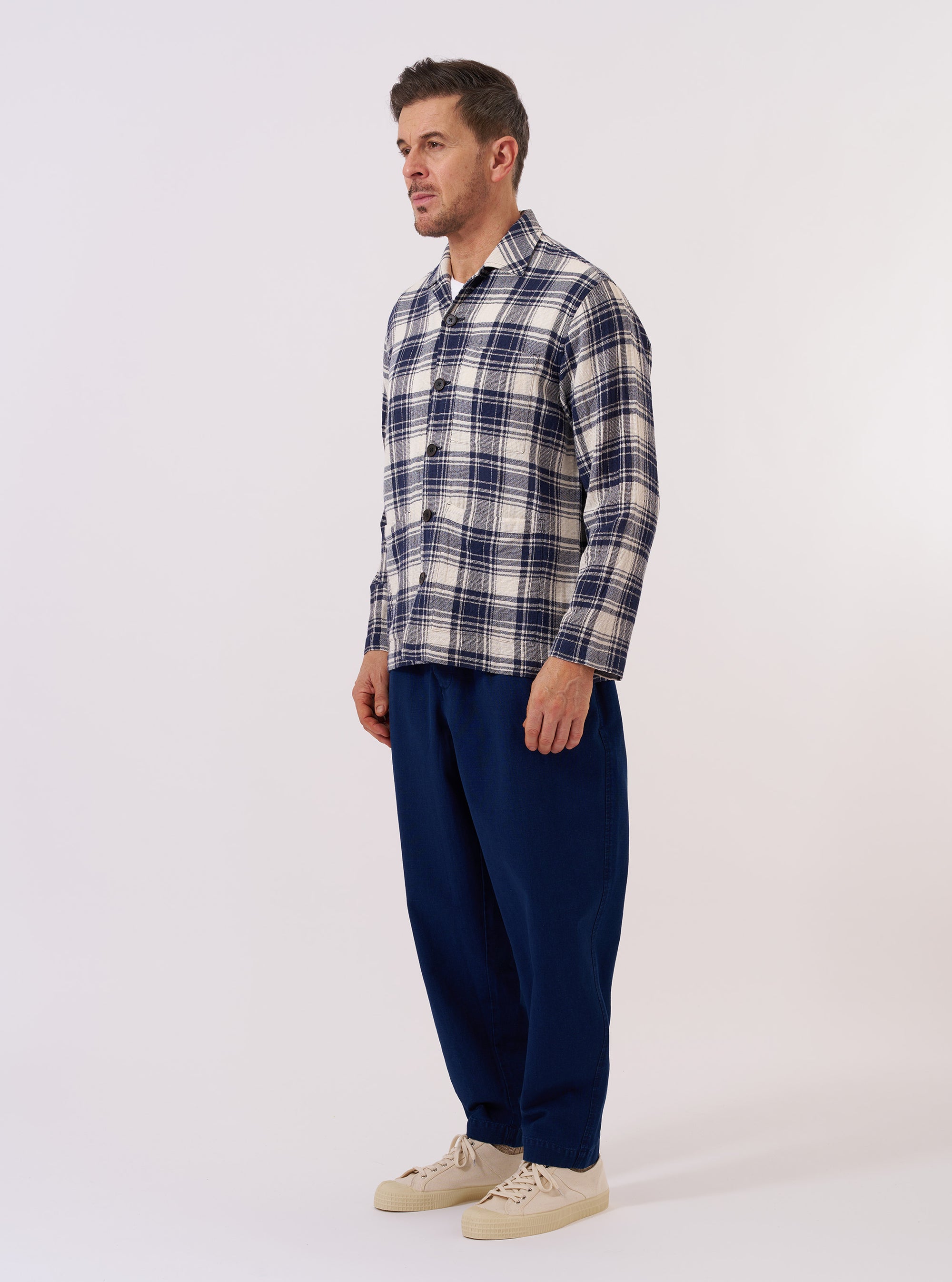 The Navy Texture Plaid Cancun Jacket is shown as a flat lay against a white background. The jacket features a revere collar, a three-button front closure, one chest pocket, and two large patch pockets at the waist. The fabric has a distinct navy blue textured plaid pattern.