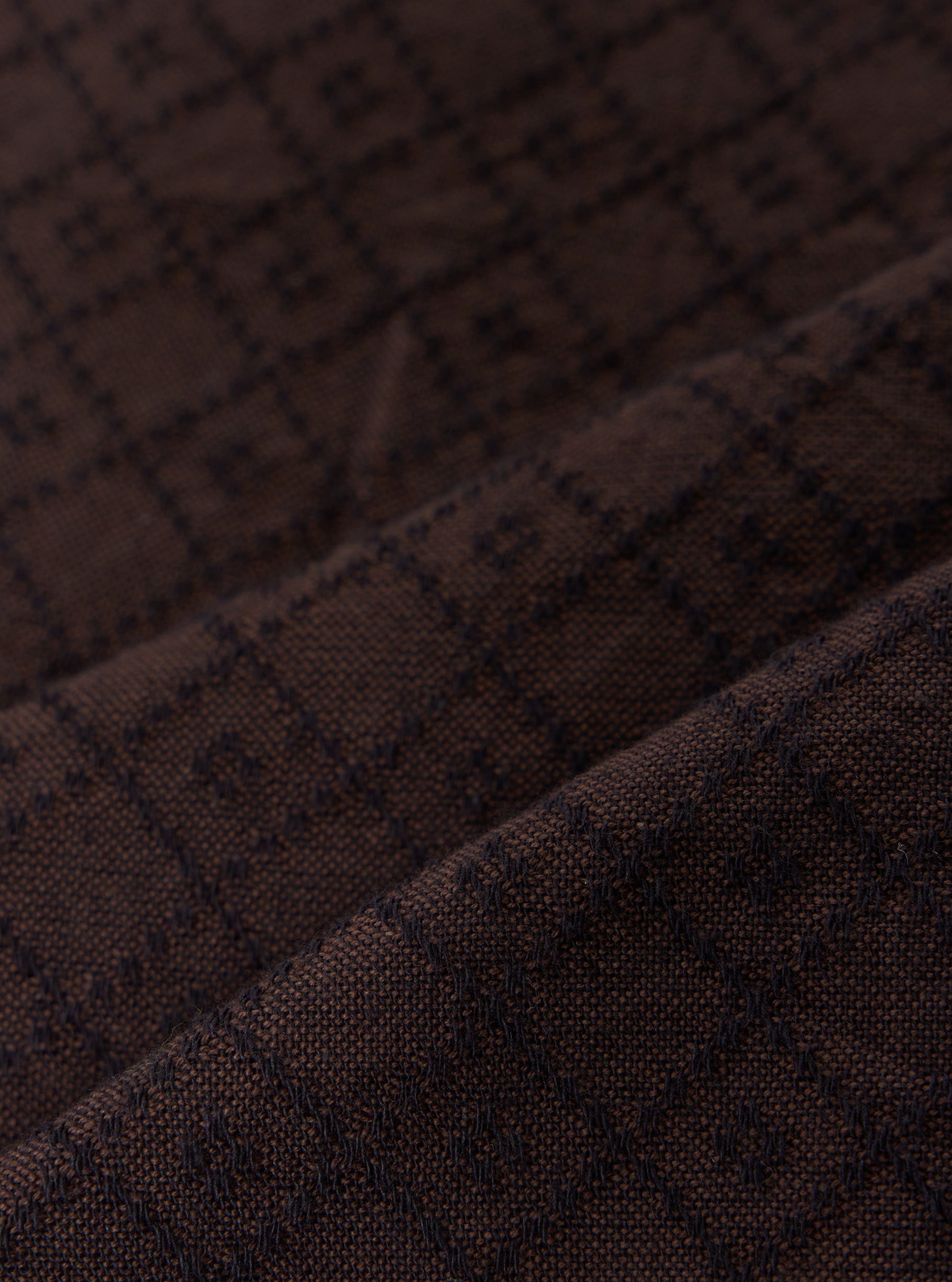 A close-up swatch image of the Brown Diamond Dobby Deck Shirt highlights the intricate textile detail. The brown cotton fabric features a distinct diamond dobby weave, creating a subtle geometric pattern with small raised stitches throughout.