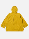 The Yellow British Wax Cotton Boston Parka is shown from the back as a flat lay against a plain white background. The image highlights the parka's matte yellow waxed cotton fabric, featuring a large adjustable hood and a prominent inverted box pleat at the center back. The garment has a straight hem and two-piece sleeves.