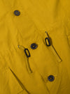 The Yellow British Wax Cotton Boston Parka is shown from the rear three-quarter angle as a flat lay against a plain white background. The image highlights the oversized silhouette, the large hood, and the inverted box pleat at the center back. The yellow waxed cotton fabric has a smooth, matte finish.