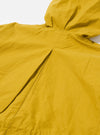 The Yellow British Wax Cotton Boston Parka is shown from a rear three-quarter angle as a flat lay against a plain white background. The image highlights the oversized silhouette, the large hood, and the inverted box pleat at the center back. The yellow waxed cotton fabric has a smooth, matte finish with visible tonal stitching along the seams and hem.