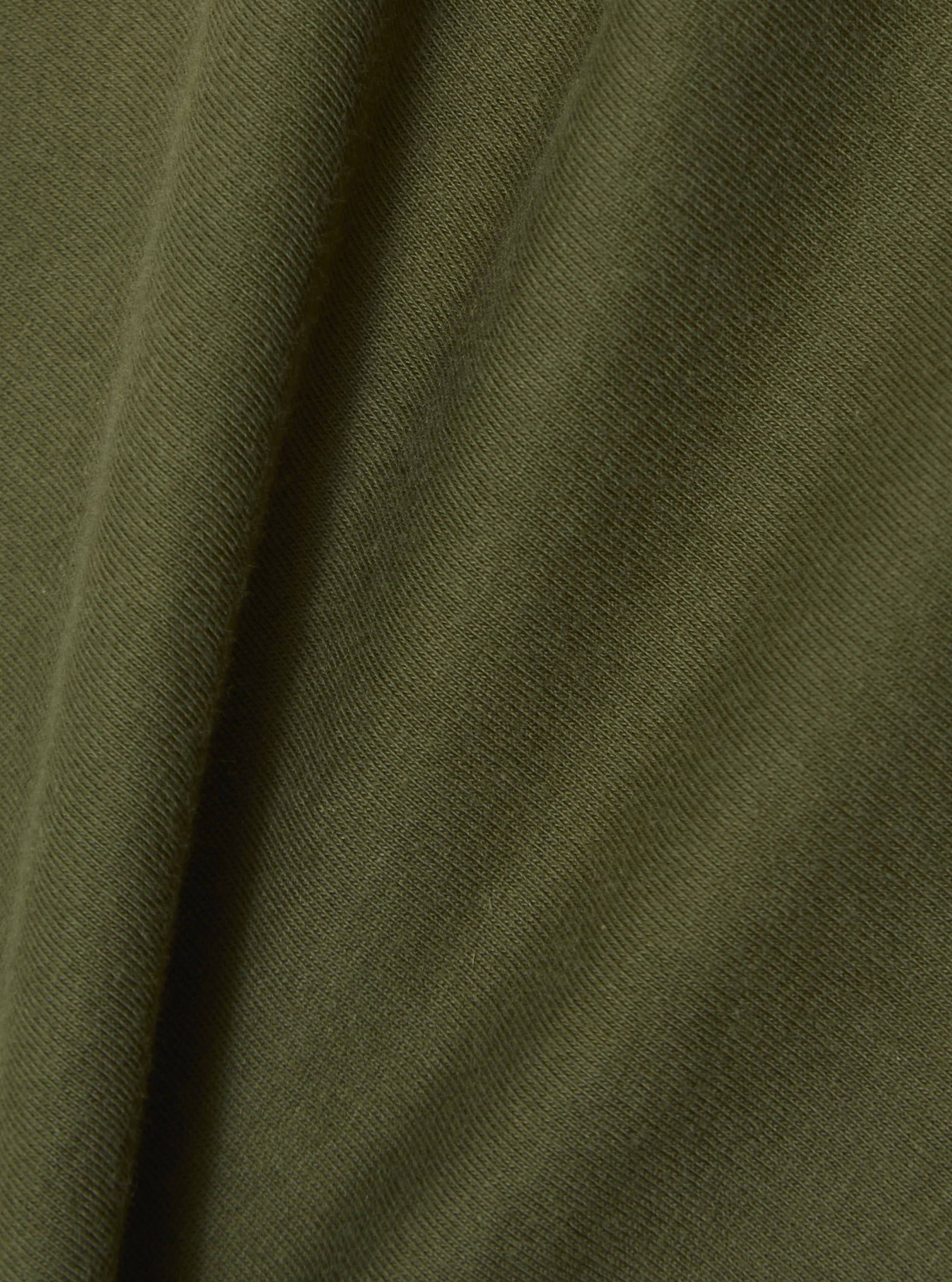 Close-up of the olive single jersey fabric of the A. SOCIETY x Universal Works tee. The soft, textured material is draped to show its quality.