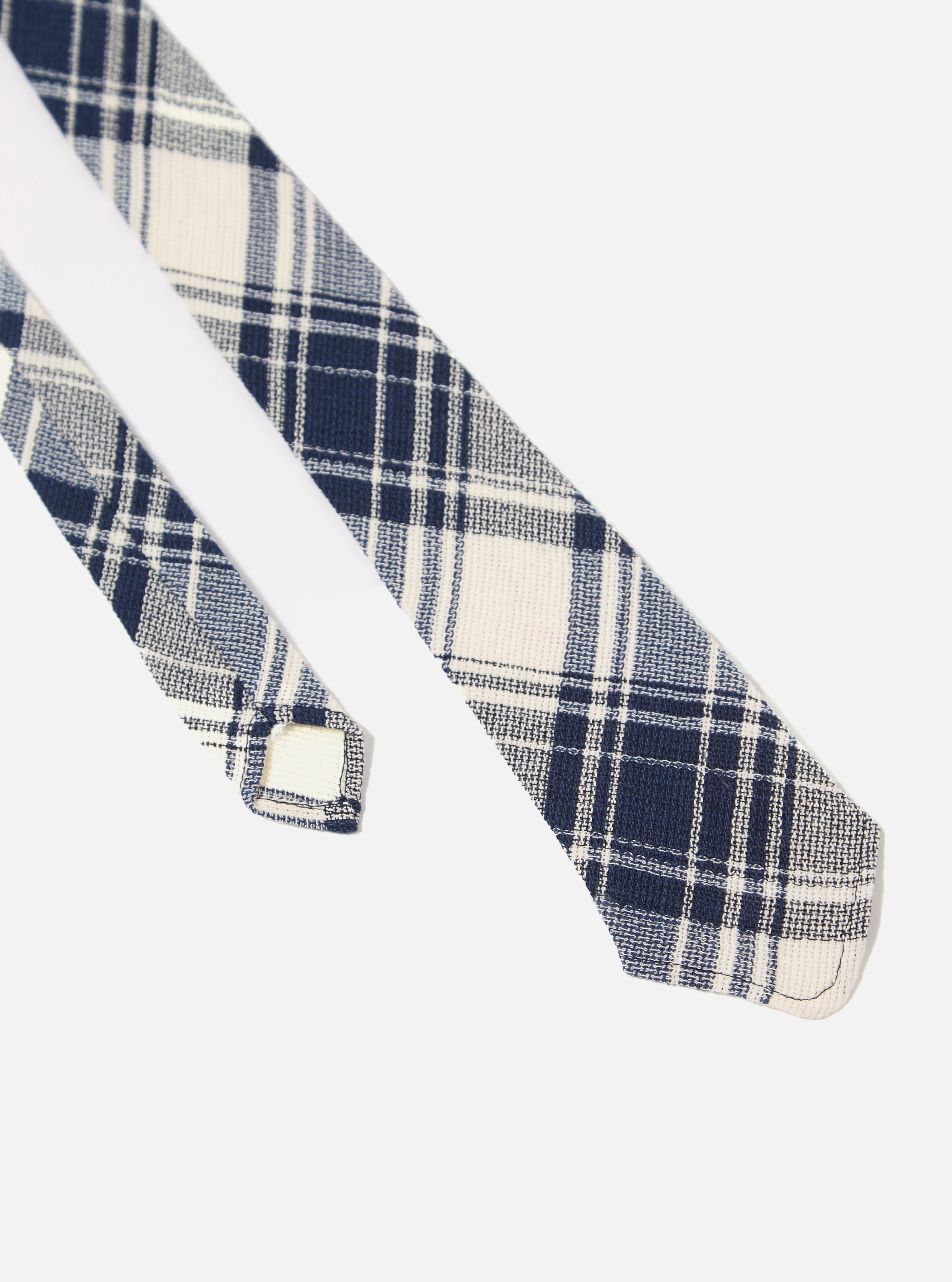 The Navy Texture Plaid Tie is shown in a close-up detail shot as a flat lay against a plain white background. The image highlights the intricate plaid pattern and the textured weave of the navy blue cotton fabric.