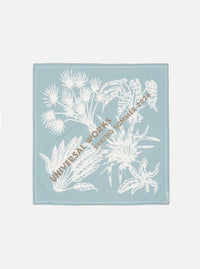 The Pale Blue Cambric Neckerchief is shown as a flat lay against a white background. The neckerchief is folded into a square, highlighting the smooth, fine weave of the light blue cambric cotton fabric and its clean, stitched edges.