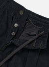 The Black Organic Fine Cord Oxford Pant is shown as a flat lay against a plain white background. The image focuses on the rear of the trousers, highlighting the elasticated waistband, a buttoned flap pocket on the left, and a buttoned jetted pocket on the right. The fine-ribbed texture of the black organic cotton corduroy is visible throughout the garment.
