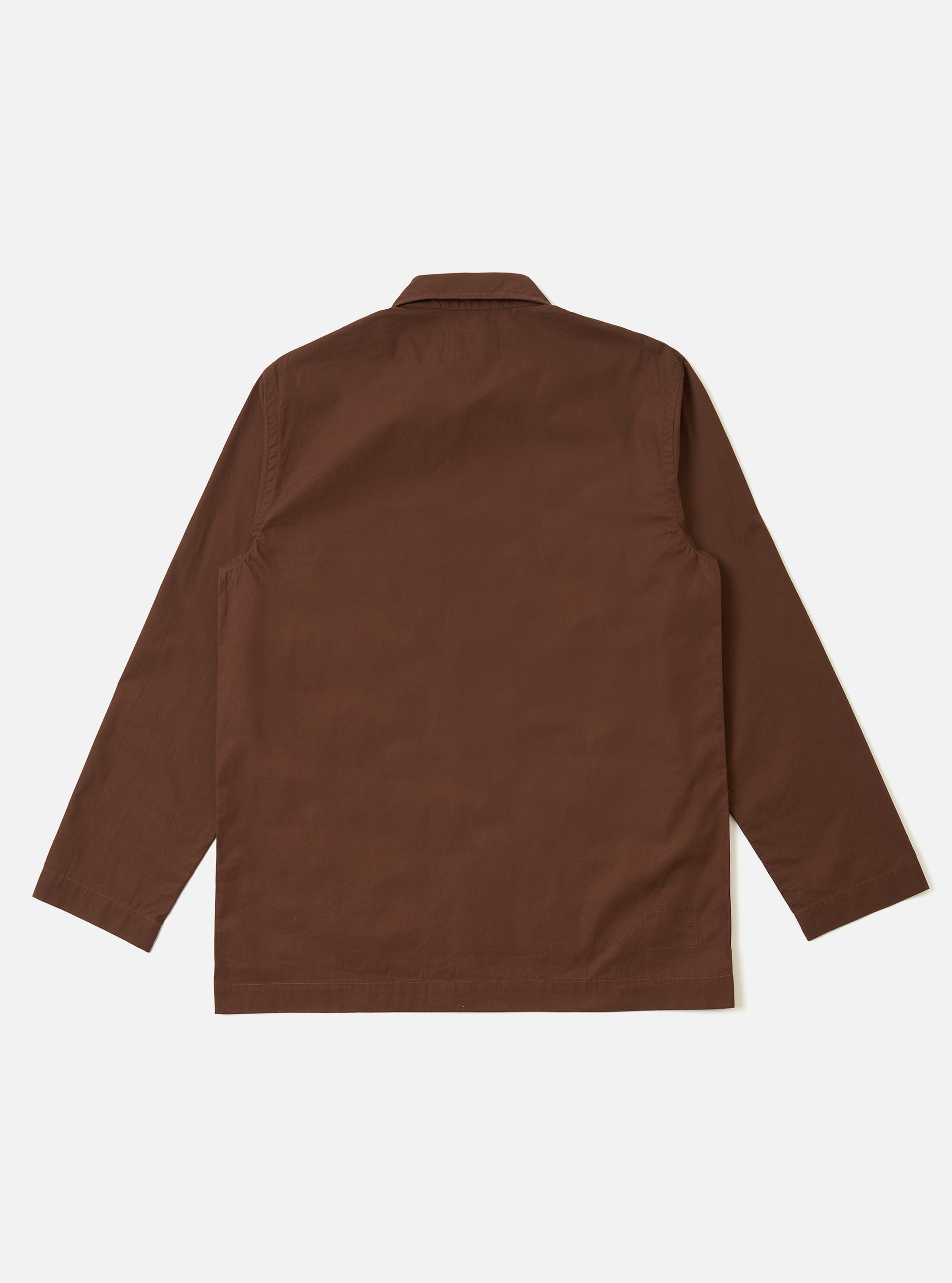The Brown Peached Poplin Bakers Overshirt is shown from the back as a flat lay against a plain white background. The image highlights the clean construction of the garment's rear panel, featuring a simple straight yoke and a slightly curved hem. The cotton poplin fabric has a smooth, matte brown finish with visible stitching details.