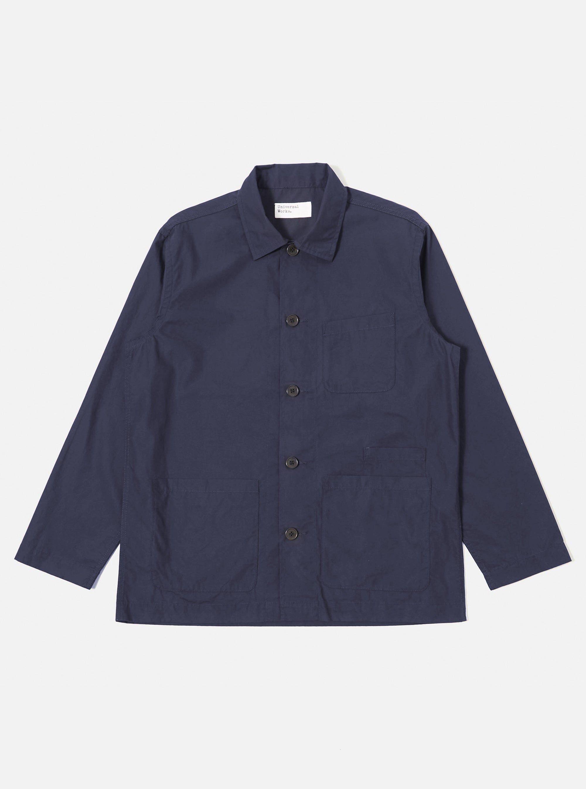The Navy Peached Poplin Bakers Overshirt is shown as a flat lay against a white background. The overshirt features a classic collar, a central button-down closure, and four front patch pockets: one asymmetric chest pocket and three lower pockets, including a small partially concealed coin pocket. The navy cotton fabric has a soft, matte finish.