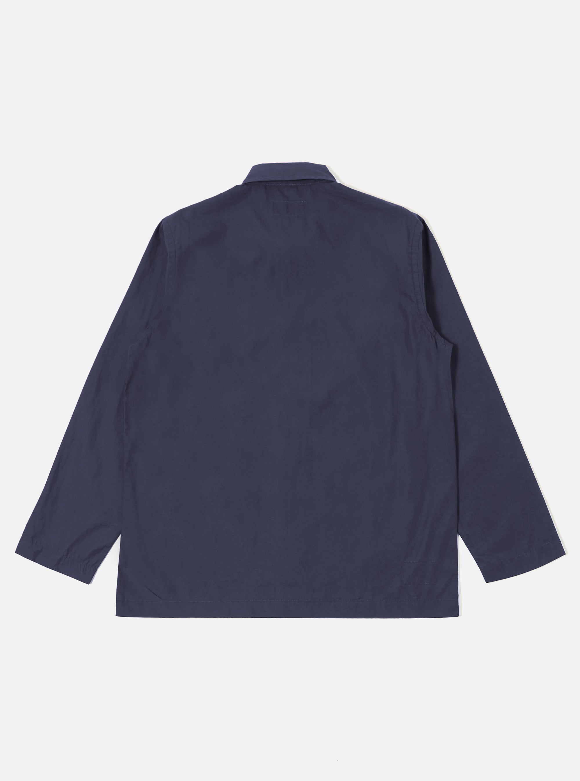 The Navy Peached Poplin Bakers Overshirt is shown from the back as a flat lay against a plain white background. The image highlights the garment's simple, straight-cut back panel, a one-piece collar, and a straight hem. The dark navy cotton fabric has a smooth, matte peached finish.