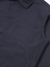 The Navy Peached Poplin Bakers Overshirt is shown from the back as a flat lay against a plain white background. The image highlights the clean, straight-cut hem, the one-piece collar, and the smooth texture of the navy blue peached cotton poplin fabric.
