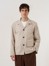 A model wears the Brown Kennedy Stripe Franck Jacket over a white t-shirt, standing against a plain white background. The jacket features a distinct vertical pinstripe pattern on brown cotton fabric. It is designed with a three-button front closure, a structured collar, and three large patch pockets—one at the chest and two at the waist. The model is shown from the front, highlighting the garment's relaxed, boxy fit.