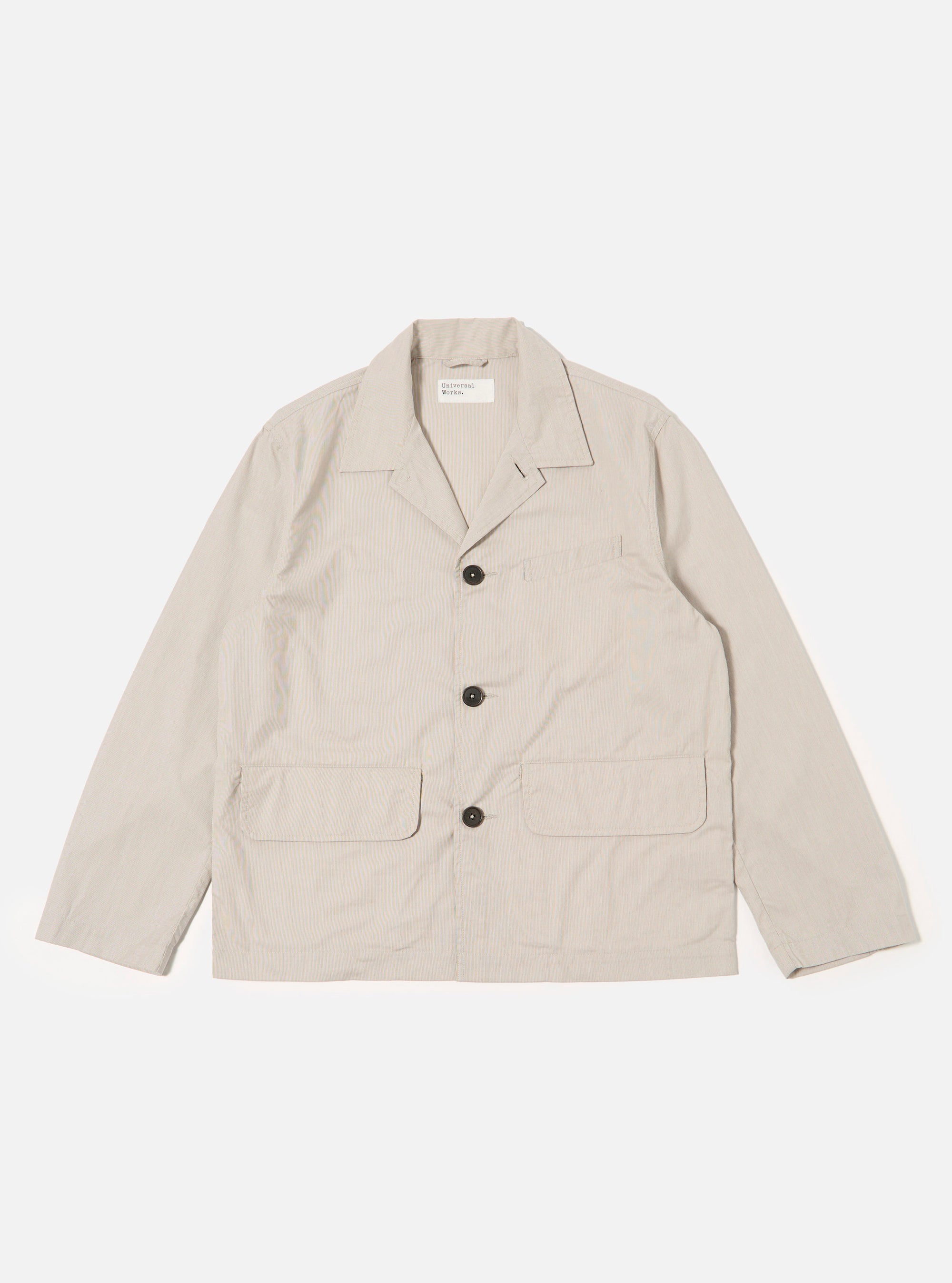 The Brown Kennedy Stripe Franck Jacket is shown as a flat lay against a plain white background. The jacket features a notched lapel, a three-button front closure, and two large patch pockets at the waist. The fabric is a brown woven cotton with a subtle Kennedy stripe pattern.
