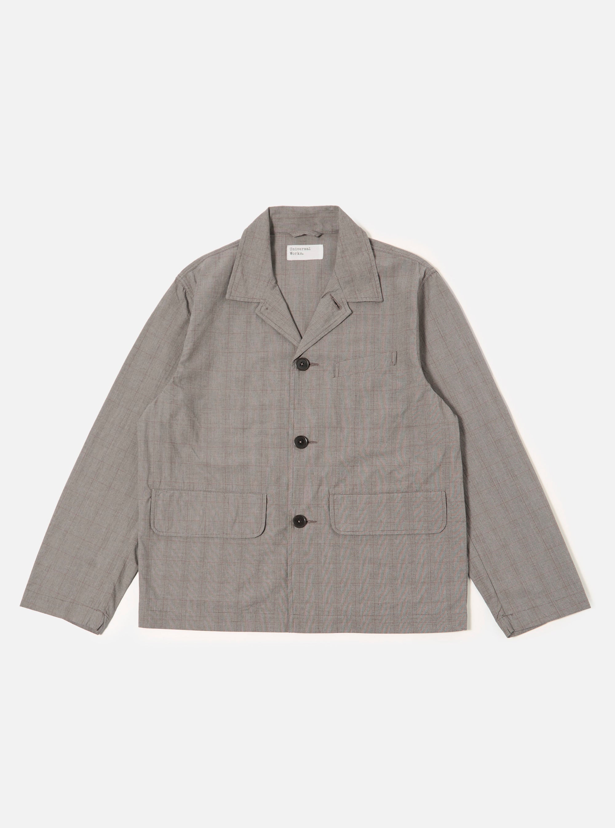 The Grey Brown Wales Glen Check Franck Jacket is shown as a flat lay against a plain white background. The jacket features a classic glen check pattern in shades of grey and brown, a central four-button closure, and three front pockets, including one chest welt pocket and two larger flap pockets at the waist. The garment is constructed with a flat collar and a straight hem.