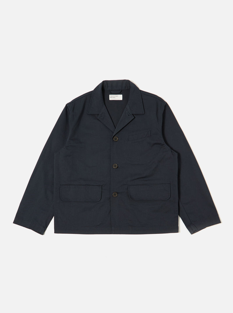 The Navy Twill Franck Jacket is displayed as a flat lay against a plain white background. The jacket features a one-piece flat collar, a central button-front closure, one welt chest pocket, and two large flap pockets at the hips. The garment is made from a structured navy blue cotton twill.