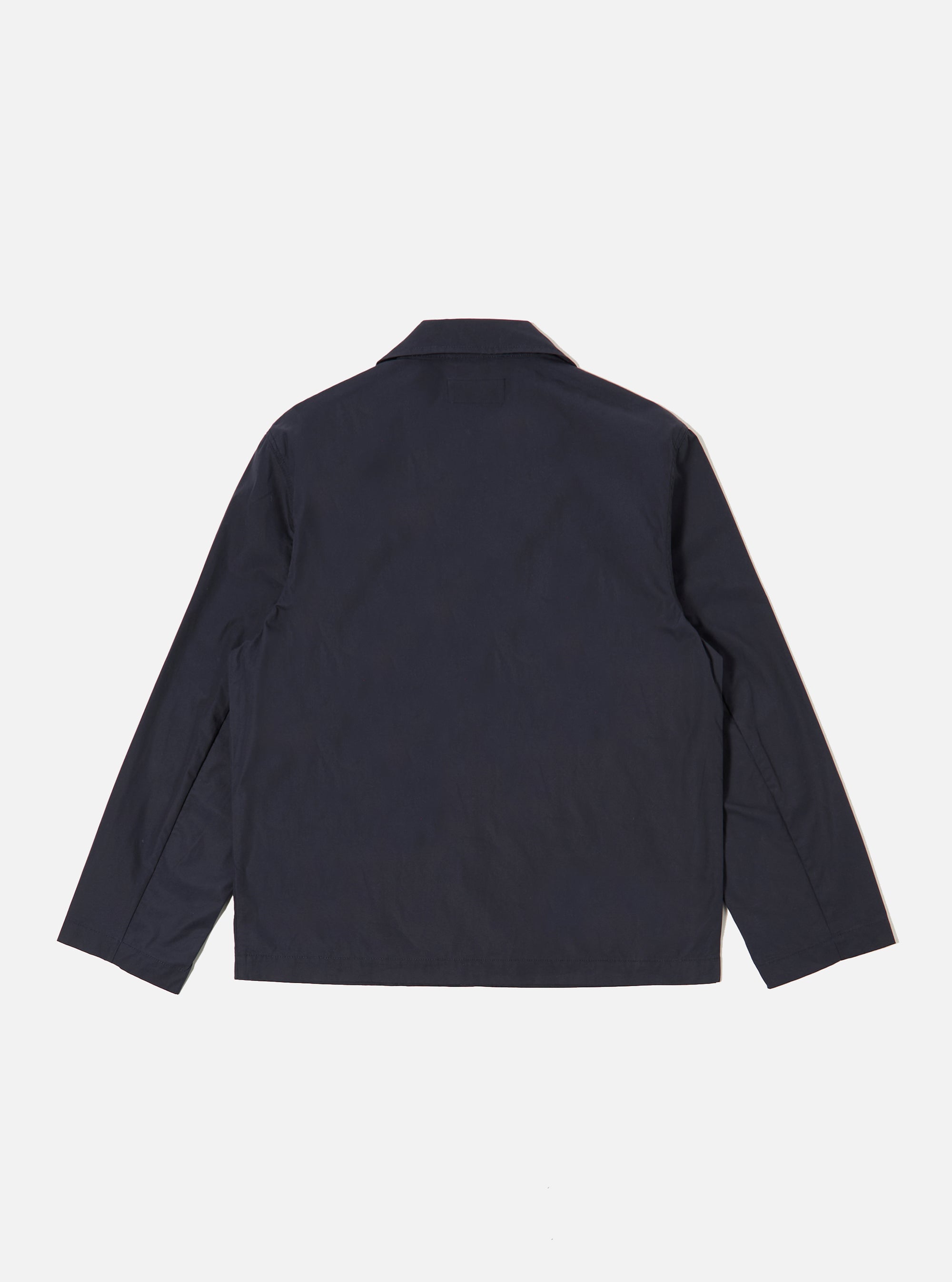 The Navy Peached Poplin Franck Jacket is shown from the back as a flat lay against a plain white background. The image highlights the clean construction of the garment's rear panel, the straight hem, and the smooth texture of the navy blue peached poplin fabric.